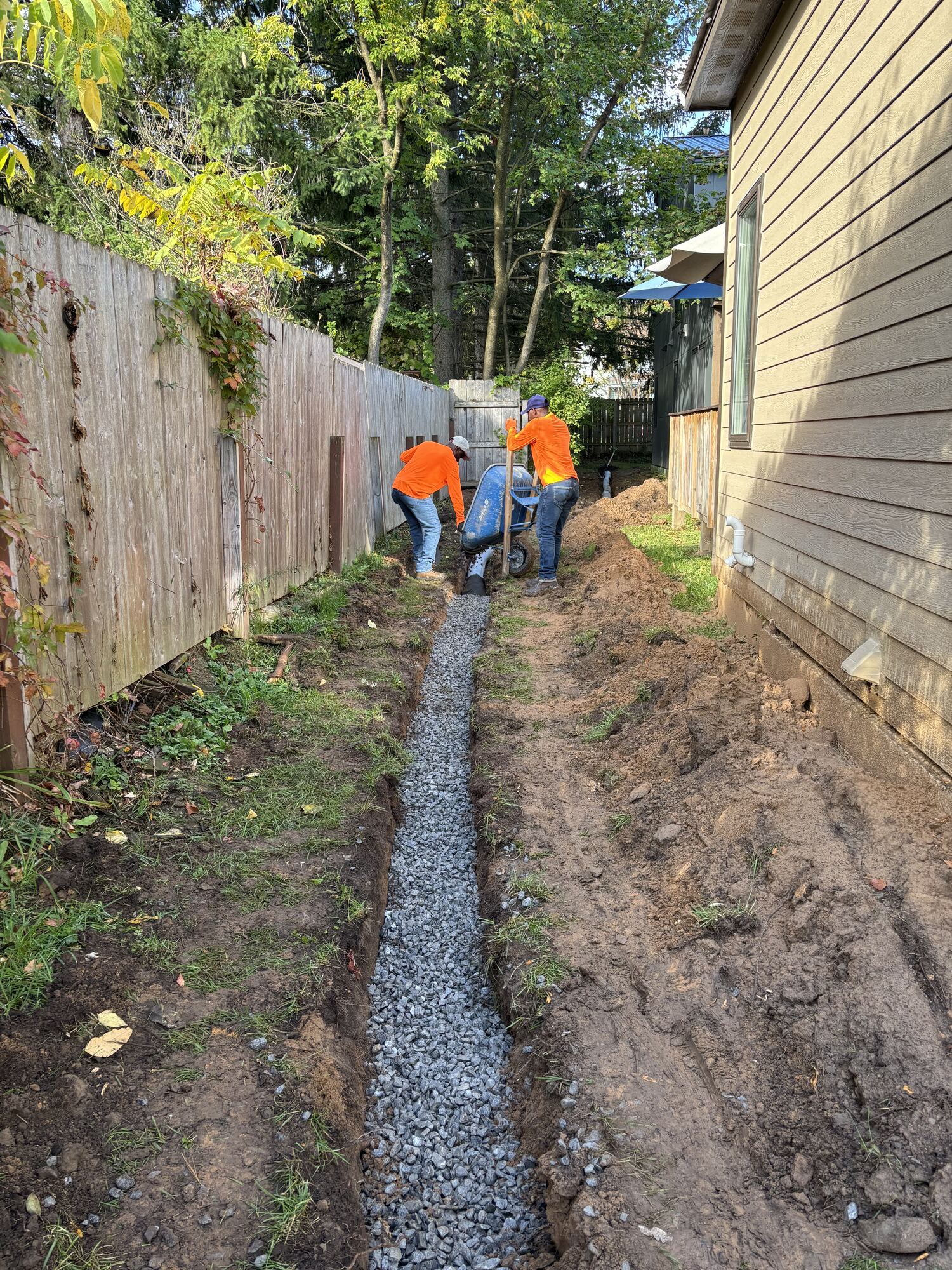 Gravel-filled French drain trench running between two houses